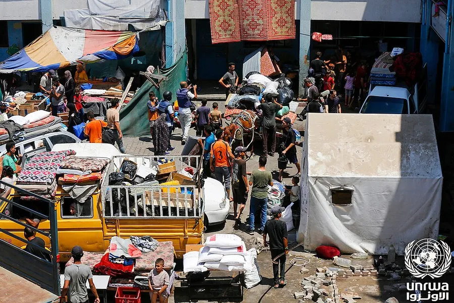Palestinos desplazados con sus pertenencias y sacos de ayuda en una escuela de la UNRWA en Deir al-Balah